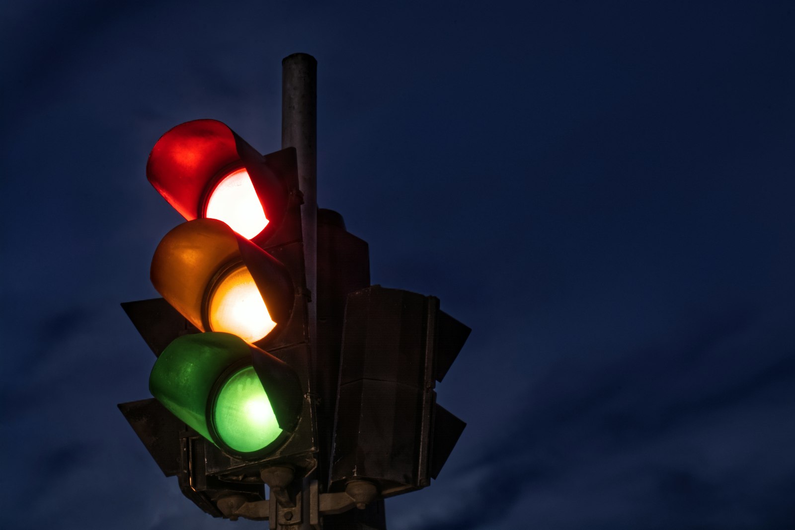 A traffic light glowing red, amber and green against a night sky — coordination signals between sessions.